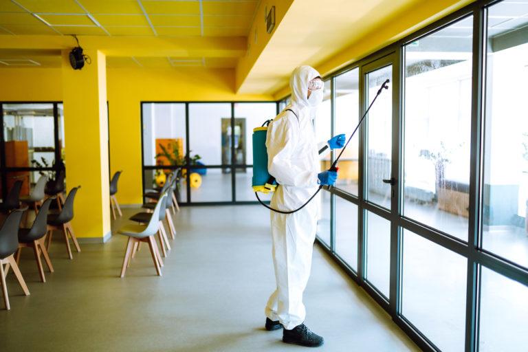 Disinfecting of office to prevent COVID-19, Man in protective hazmat suit. Cleaning concept