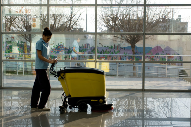 A Man worker cleaning the floor with scrubber machine